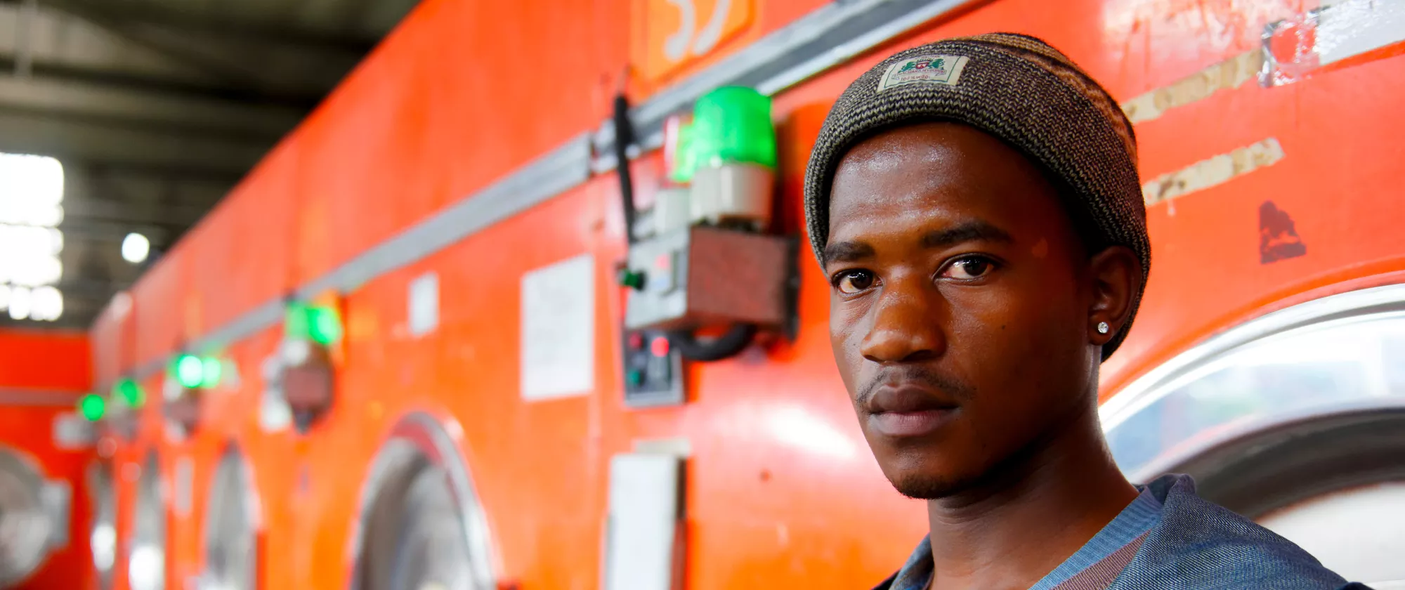 Young man stands before orange washing machines