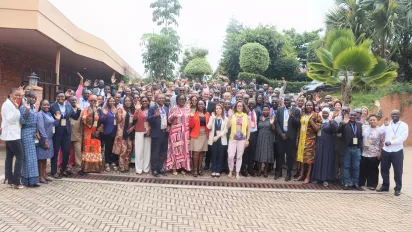 Participants to the regional academy on fundamental principles and rights at work pose for a group photo, they are around 100 and some of them raise their hand in the photo