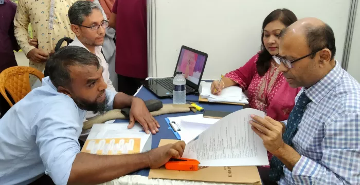 A person with physical disabilities speaks with a prospective employer at a job fair held in Chattogram, Bangladesh