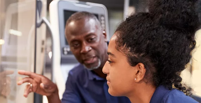 An engineer showing a young female apprentice how to use CNC Tool Making Machine