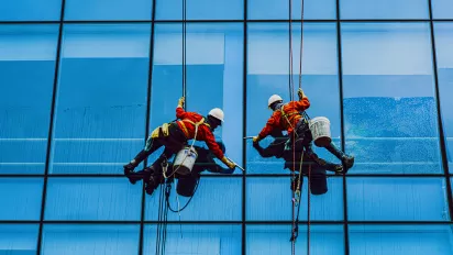 Two men painting on a building