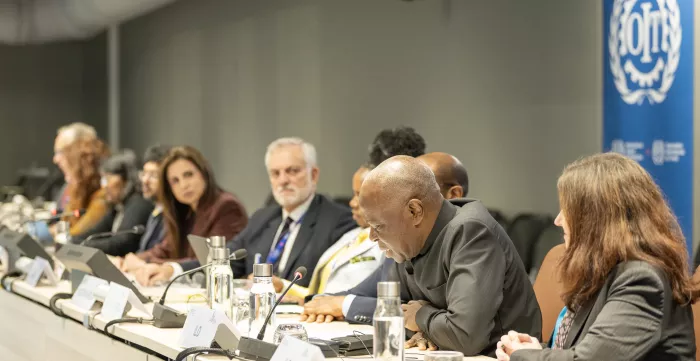 Row of mean and women behind a desk with ILO logo behind them