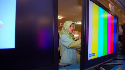 a woman worker with two TV screens in a factory