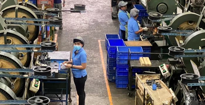 Female workers operate machinery at an automotive parts manufacturing company in Thailand.